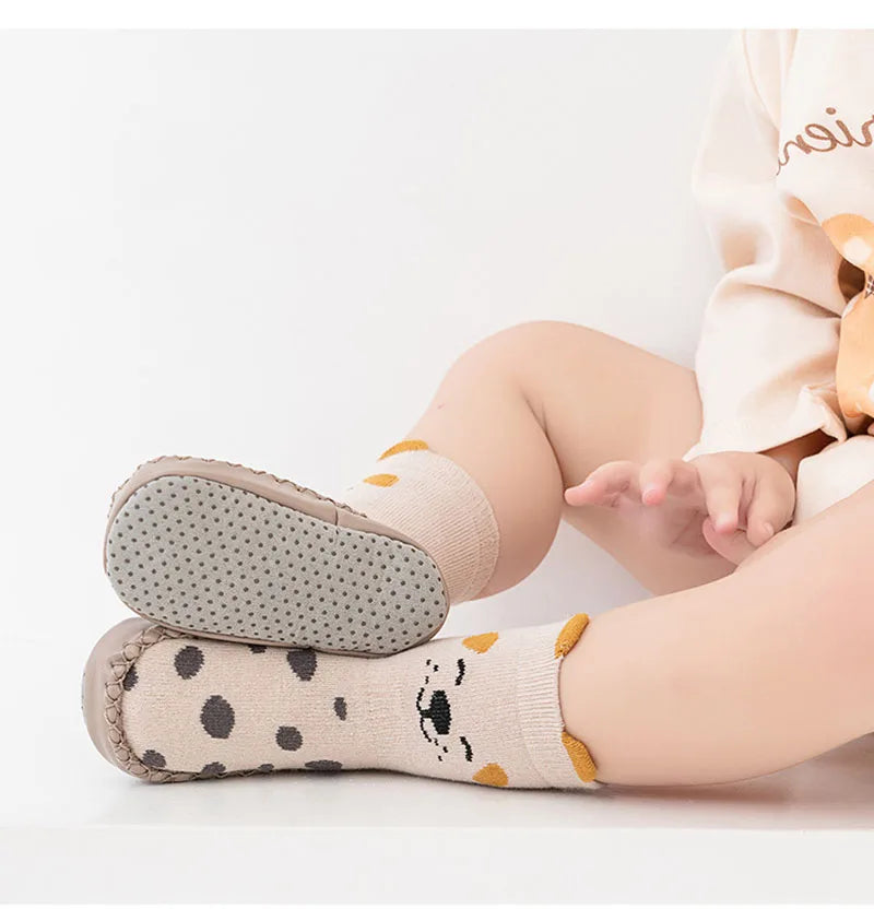 A pair of beige cartoon non-slip baby socks for toddlers with a textured sole and cute animal print.