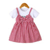Girls' cotton knit dress in red and white plaid with a bow accent displayed on a hanger.