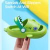 A hand holds a green kids shark clog sandal, demonstrating the switch at will feature.