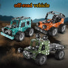 Three metal building block off-road vehicles, including an excavator and a truck, displayed on a dirt surface.
