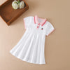A white kids summer cotton dress with a pink turn-down collar and a small red emblem is displayed on a neutral background.