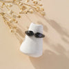 A silver ring with a cat and puppy paw print design rests on a light-colored surface next to dried floral branches.