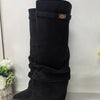 Black knee-high chunky heel boots with a metal buckle displayed on a surface.