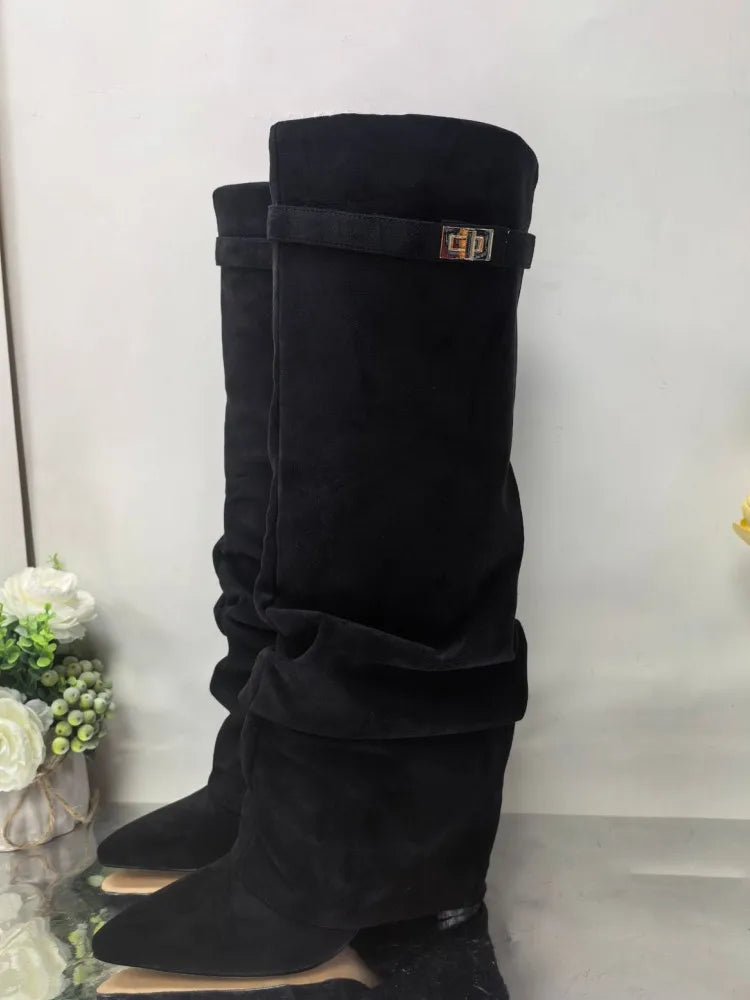 Black knee-high chunky heel boots with a metal buckle displayed on a surface.