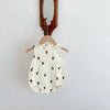 A cream-colored baby cotton sleeveless jumpsuit bodysuit set hanging on a wooden hanger against a white wall.