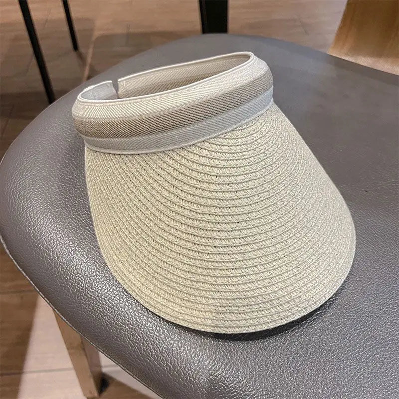 A woven straw sun hat with a light beige brim resting on a gray table.