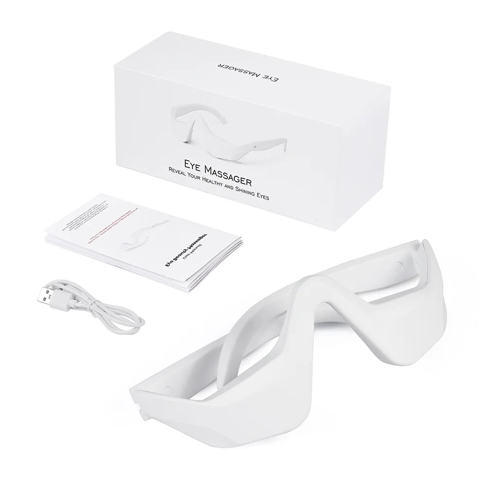 White eye massager device and accessory lying on a white box.
