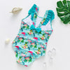 A turquoise one-piece swimsuit with a floral and tropical bird print featuring pink, green, and yellow flowers.