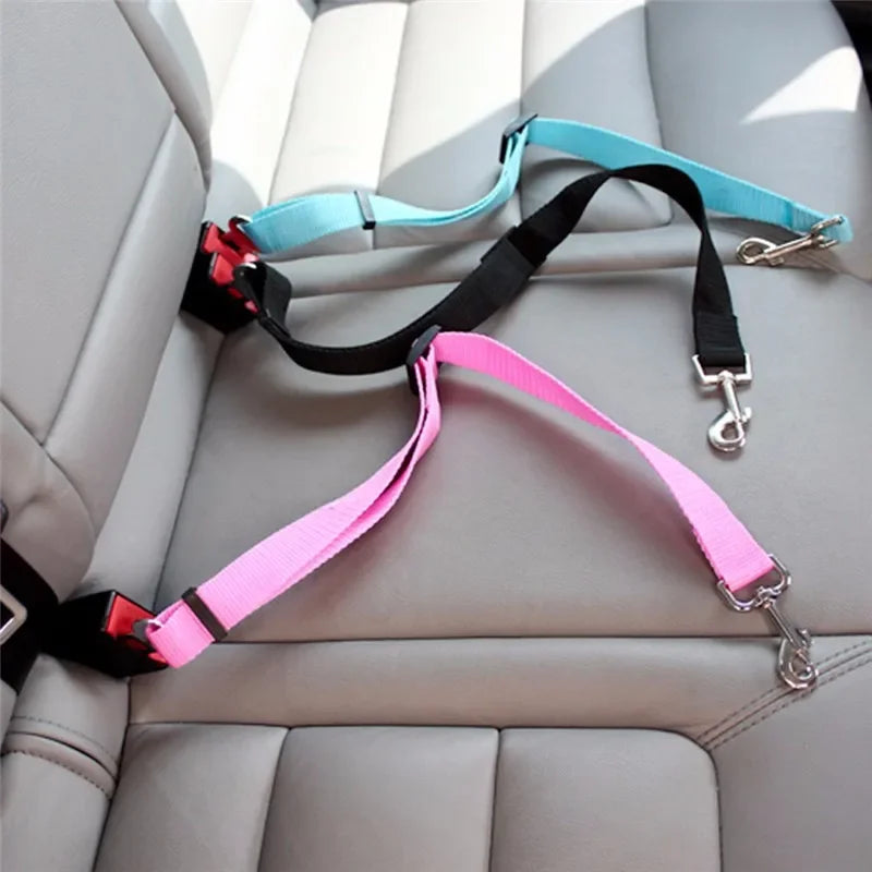 Correas ajustables de arnés de seguridad para mascotas en negro, rosa y azul claro sobre un asiento de coche.