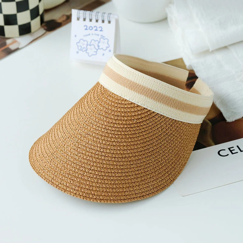 A woven straw sun hat with a light beige brim resting on a white surface.