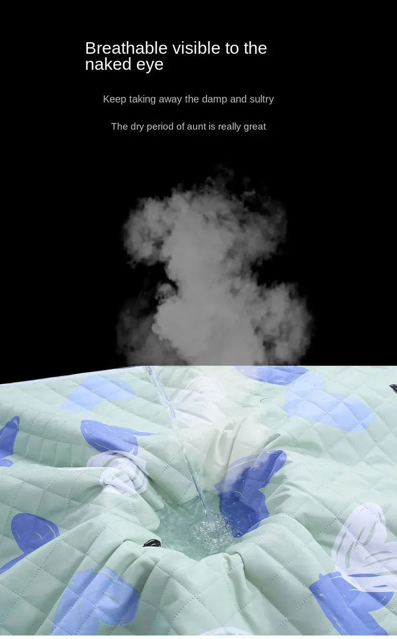 A light green quilted mattress protector with a blue cartoon pattern is shown, featuring visible steam or vapor.