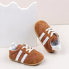 A pair of brown baby first walker shoes with white stripes and a light gray sole are shown against a white background.
