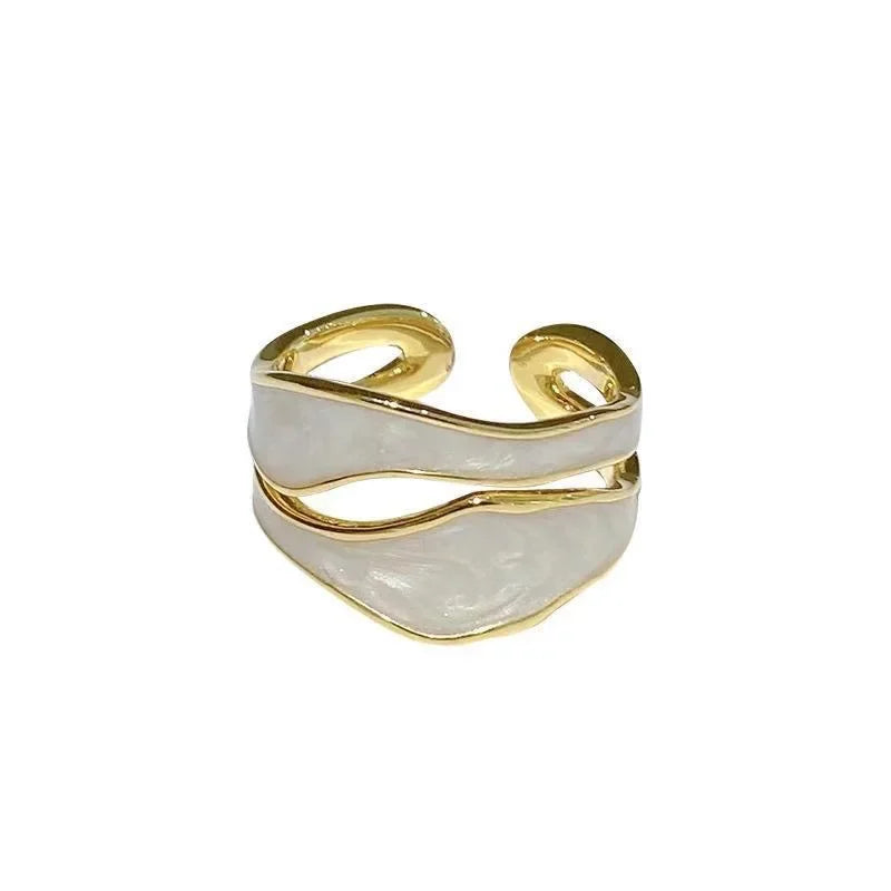 En gullfarget ring med uregelmessig geometrisk emalje og justerbart åpent design.