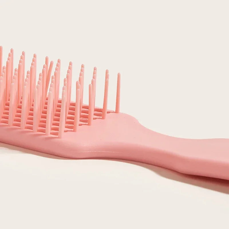 Peine desenredante rosa con nueve púas, en una superficie clara.