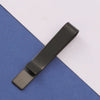 A dark metal tie clip lying diagonally on a blue-gray fabric surface.