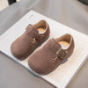 A pair of brown retro non-slip kids' moccasin shoes with an easy hook-and-loop closure resting on a white surface.