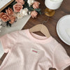 Pink girls cotton lace hem short sleeve tee displayed on a wooden surface with roses and a hanger