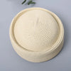 A beige straw pillbox sun hat with a wide brim shown against a light gray background.