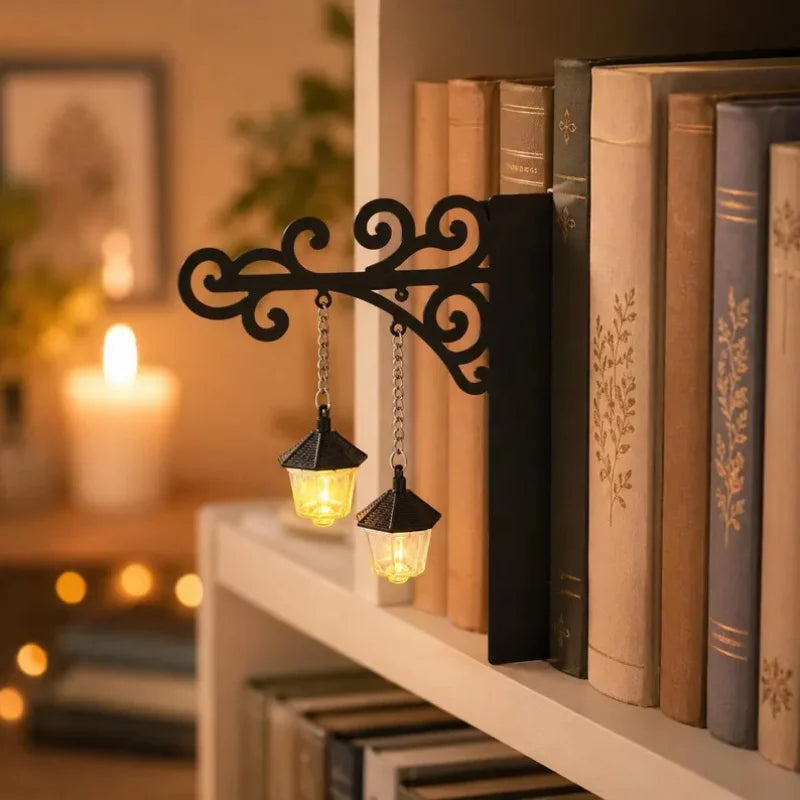 A black wrought iron shelf lamp with a glass lantern hangs over a stack of old books on a white shelf.