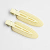 A set of two pale yellow matte resin side hair clips lying on a white background.