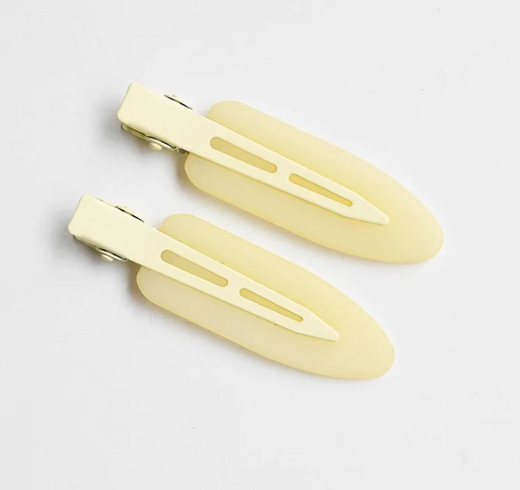A set of two pale yellow matte resin side hair clips lying on a white background.