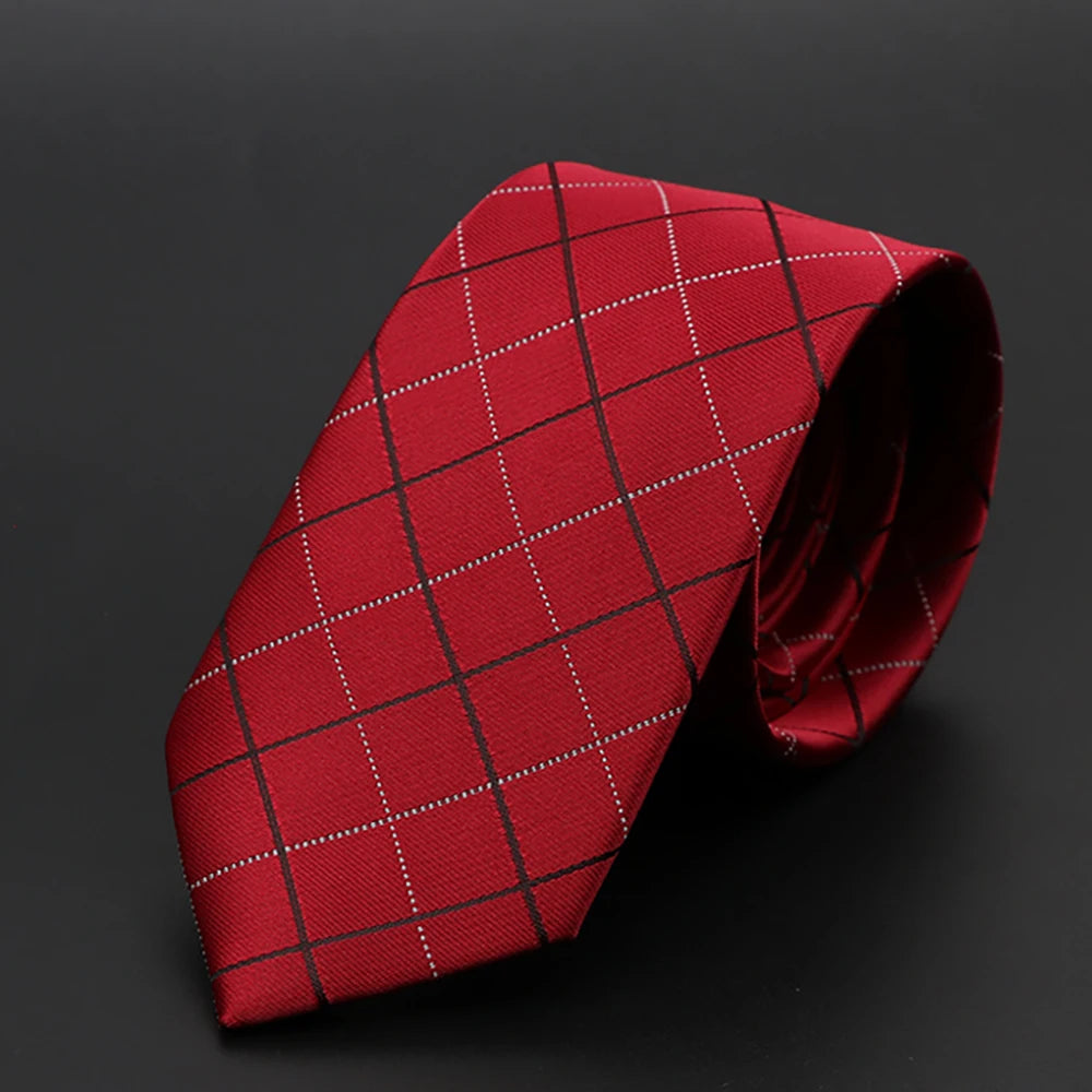 Corbata roja a cuadros con líneas blancas diagonales, doblada sobre un fondo oscuro.