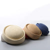 A beige straw pillbox sun hat is shown next to a blue knitted hat.