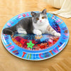 Un gato gris y blanco yace sobre un plato azul decorado con diseños de peces coloridos.
