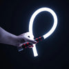 يد تمسك بمصباح عمل LED من السيليكون المرن على شكل حلقة مضيئة بيضاء على خلفية داكنة.