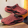 A pair of pink men's EVA slip-on sandals with cushioned platform soles resting on a wooden surface.