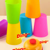 A collection of brightly colored plastic cups in various shades of green, yellow, blue, and pink are shown on a surface.