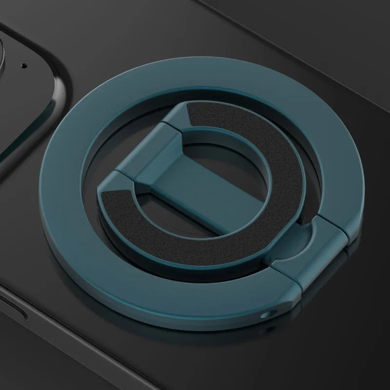 Nærbilde av en teal magnetisk ringstativ for en sammenleggbar telefon, mot en mørkegrå bakgrunn.