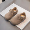 A pair of tan retro non-slip kids' moccasin shoes with an easy hook-and-loop closure resting on a white box.
