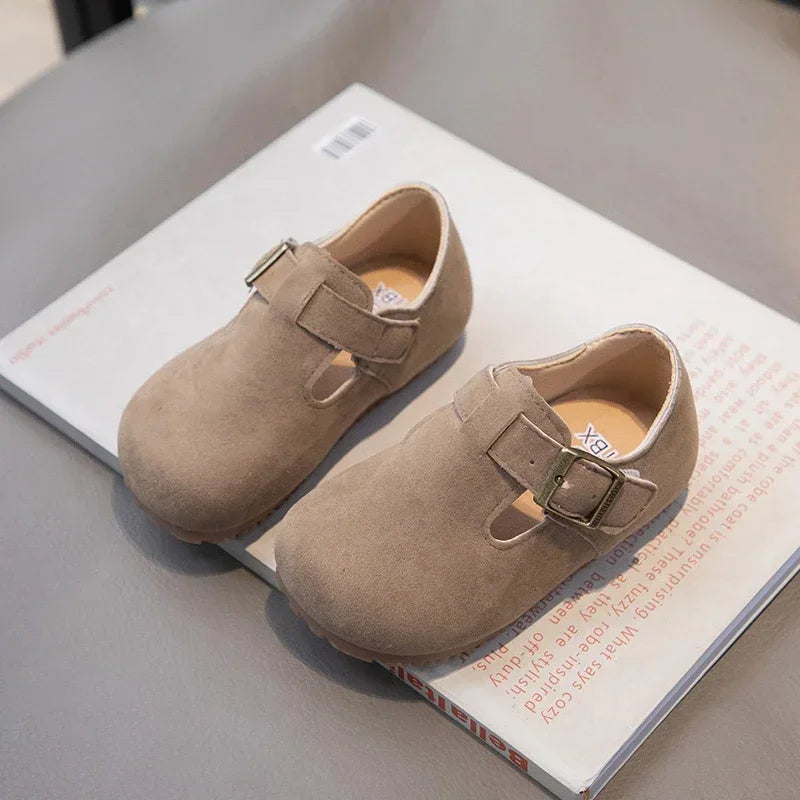 A pair of tan retro non-slip kids' moccasin shoes with an easy hook-and-loop closure resting on a white box.