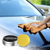 A hand is applying ceramic car wax to a blue car surface using a yellow applicator sponge.