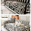 Geometrisch gemusterte Couchdecke in Schwarz-Weiß mit Fransen, Vorder- und Rückseite.