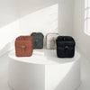 A collection of four vintage vegan leather messenger bags in shades of brown, gray, and black displayed on a white pedestal.