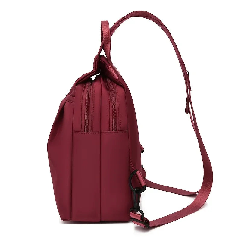 A maroon lightweight Oxford cloth mini backpack with a brown leather strap is shown against a white background.