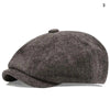 A dark gray vintage newsboy cap with a folded brim shown from the side.