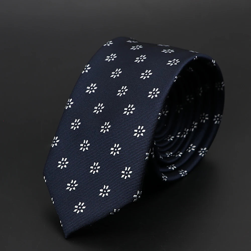 Corbata azul oscura con diseño floral blanco sutil, doblada y exhibida sobre fondo oscuro.