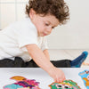 A child is working on a jumbo-sized puzzle featuring colorful, playful aesthetics.