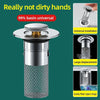 A silver press-type sink drain stopper with a mesh filter and a removable cap.