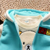 A light blue fleece jacket and matching top with a cartoon bear design, displayed on a woven mat.
