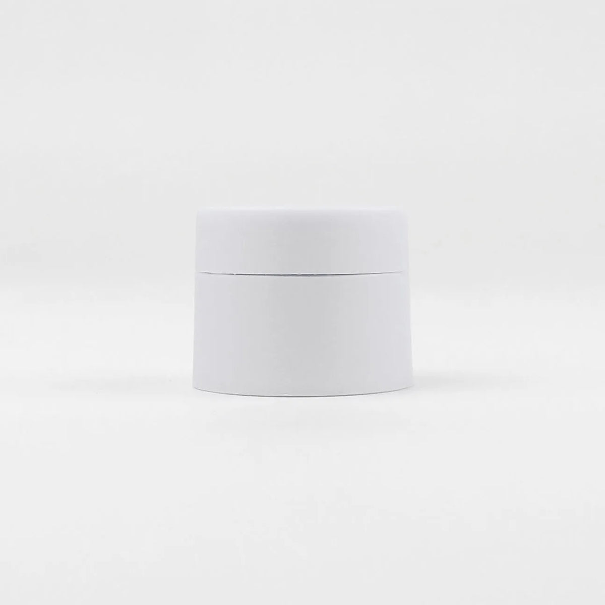 A white jar of refillable travel face cream with a leak-proof lid.