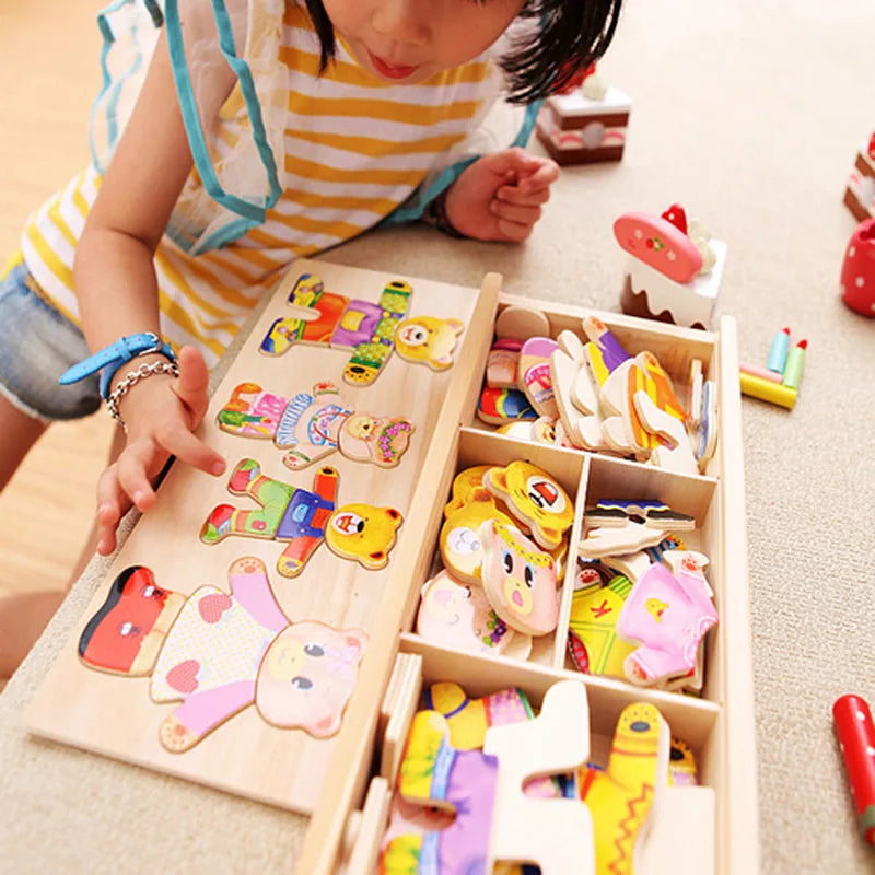 A child is interacting with a wooden puzzle set featuring bear dress-up elements and various small wooden toys.