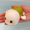 A hand holds a cute bath toy shaped like a duck with a green shell and a light pink body.