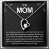 Collar con colgante de corazón plateado sobre tarjeta negra con dedicatoria para una madre.