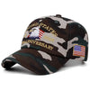 En mörk camo-basebollkeps med broderad text United States 2026 och en amerikansk flagga.