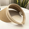 A woven straw sun hat with a wide brim is shown on a white surface.