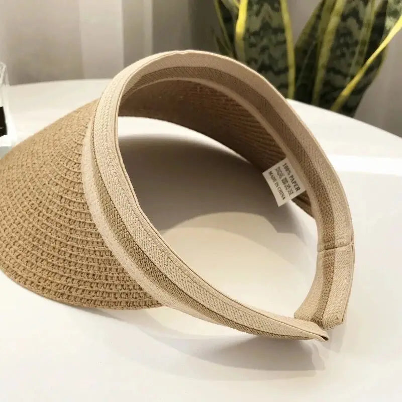 A woven straw sun hat with a wide brim is shown on a white surface.
